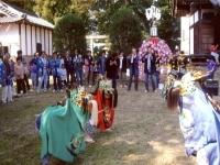 神社の境内で3頭の獅子舞が踊っており、多くの観衆が回りを囲んでいる写真