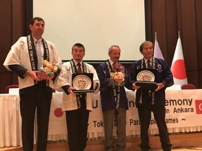 はにぽんんお人形とお皿のようなものを持って4名で記念撮影をしている写真