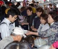 学生に炊き出しのおもてなしをしている本庄市民の写真