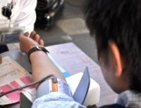 左腕の袖をまくった男性が血圧を測っている様子の写真