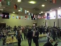 国際交流協会クリスマス会で万国旗が飾られてあるホールに大勢の人が集まっている写真