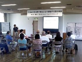スクリーンを見ながら椅子に座って話を聞いている参加者達の写真