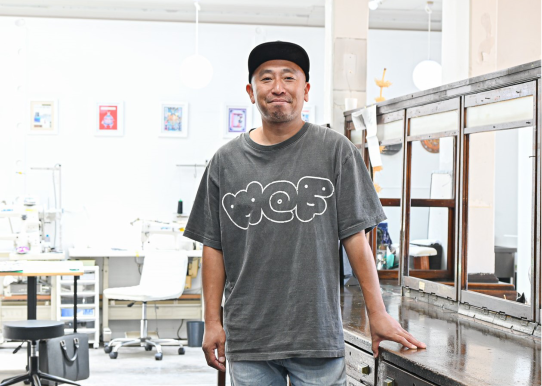 灰色のTシャツを着てキャップをかぶった笑顔の男性