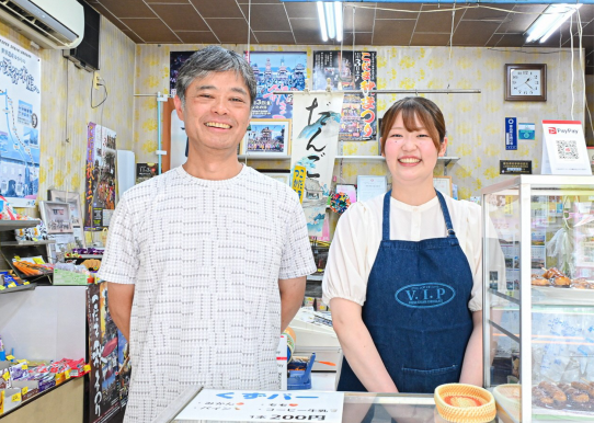 駄菓子屋のレジでほほえむ男性と女性 女性はエプロンを着ている