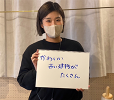 かわいい古い建物がたくさんと書かれたスケッチブックを持った女性