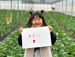 あまりんと書かれたスケッチブックを持った幼い女の子
