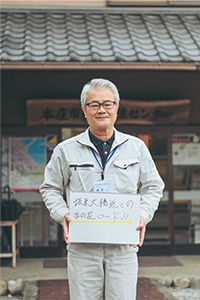 坂東大橋近くのなの花ロードと書かれたスケッチブックを持った男性