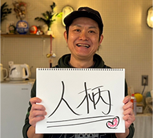 人柄と書かれたスケッチブックを持った男性