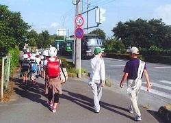 通学している小学生達の後ろを歩いている防犯ボランティア2名の方の写真