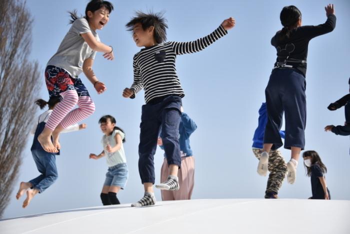空気で膨らむ遊具の上で飛び跳ねて遊ぶ子どもの写真