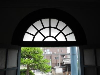 開かれた窓の上部の半円の形をしたガラス窓の写真