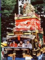武内宿禰の人形が上に立っており、高欄は赤く白い鳥の模様が描かれている本庄泉町の山車の写真