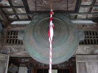 大きな成身院百体観音堂の鰐口が天井からつるされ前に紅白のひもが下がっている写真
