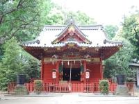 周りに木々が植えられ、社殿の壁が赤色の金鑽神社の写真