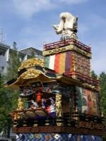 上に歌舞伎の白頭のような人形が立っており中央には3つの太鼓がある本庄本町の山車の写真