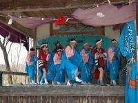 青や赤の浴衣を着た10人ほどの人が神社で踊っている写真