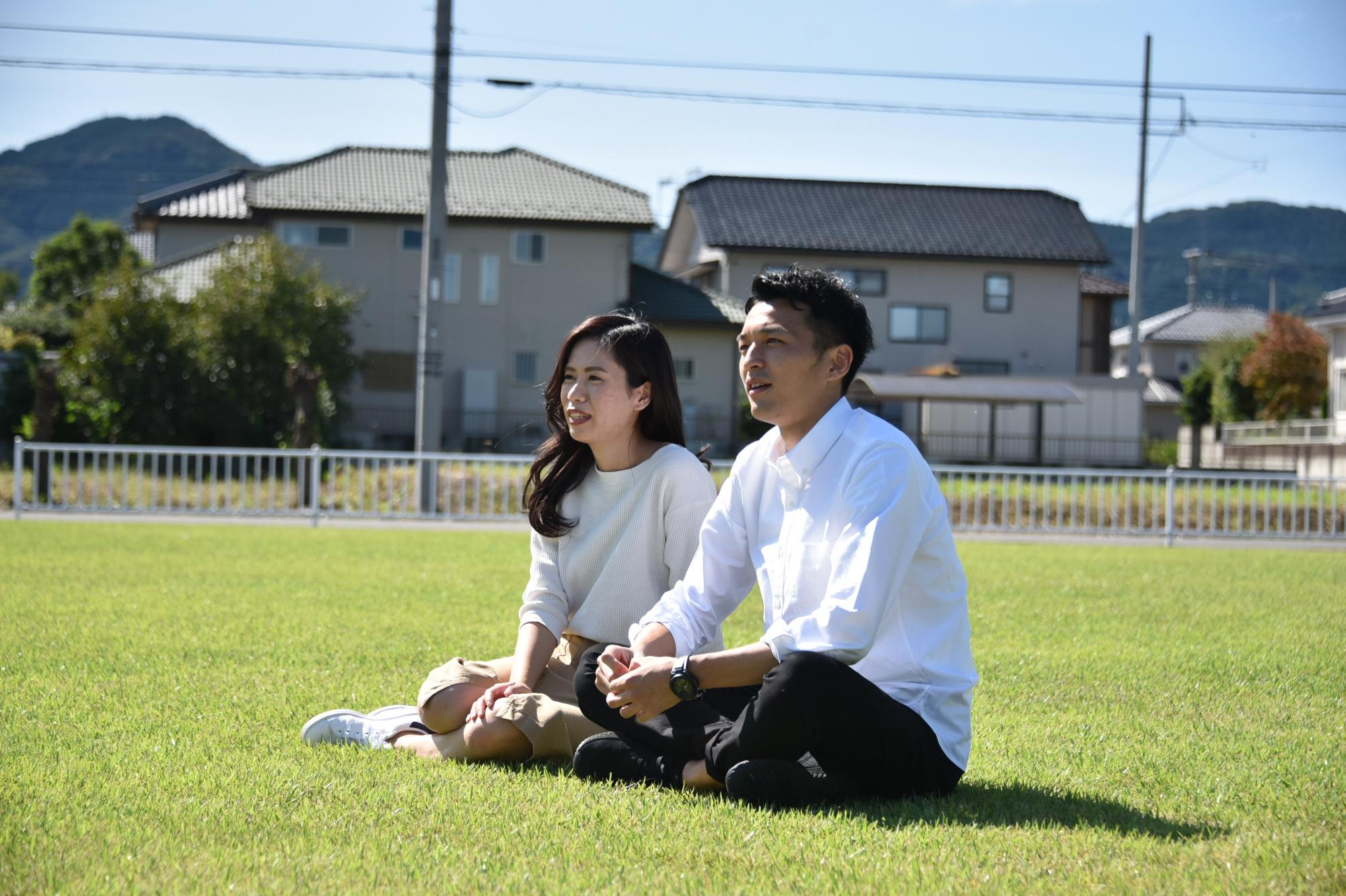公園の芝生の上で談笑する夫婦の写真