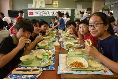 教室で給食を食べている笑顔の生徒達の写真
