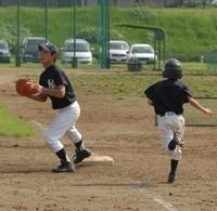 グラウンドで塁を守っている少年と塁に向かって走っている少年の写真