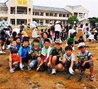 校庭に芝生を植えている子供たちの写真