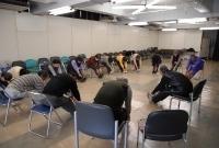 介護予防教室で椅子に座って手で足先をもつ体操をしている参加者達の写真