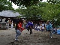 こだま夏まつりで獅子舞の衣装を着た3人が神社の境内で踊っている写真