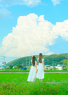 山並みと雲の風景を眺める二人の女性の後ろ姿